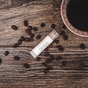 Café Mocha natural lip balm by Willow & Birch Apothecary, displayed with coffee beans and a cup of coffee, a good lip balm for dry lips and a perfect chapstick for daily cocoa butter lip therapy.