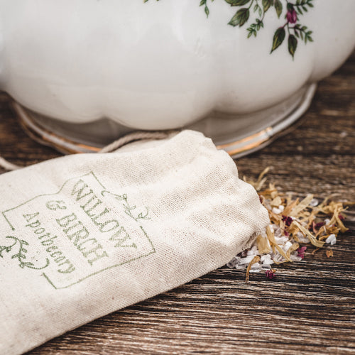 Spilled natural epson salt mixed with dried herbs beside a vintage floral teapot, emphasizing the therapeutic qualities and soothing benefit of epsom salt bath. A serene setting for spa bath salts and mineral salt bath products.