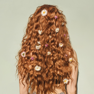 Sure! Here is the image alt text:  "A woman with red wavy hair adorned with flowers, exemplifying healthy hair tips, healthy tips for hair, healthy hair growth tips, and tips for healthy hair growth.