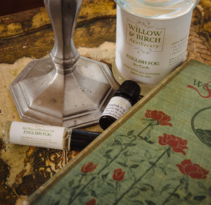English Fog scented natural artisan bath, beauty, and fragrance products by Willow & Birch Apothecary pictured with antique candlestick and antique book, inspired by Downton Abbey and Jane Austen, vintage victorian style for old souls
