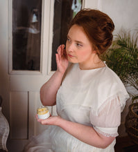 Woman in Victorian dress applying moisturizer face cream