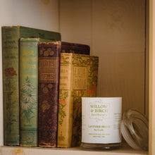 Scented soy candle by Willow & Birch Apothecary with a stack of antique books