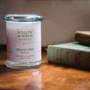 Scented soy candle by Willow & Birch Apothecary with a stack of antique books