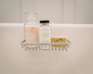 Natural Dead Sea salts and handmade soap on a bathtub caddy, featuring Willow & Birch’s epsom salt bath blends, epitomizing the best bath salts and mineral salt bath products for an experience designed for relaxation and rejuvenation.