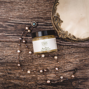 Rose Petals Day Cream by Willow and Birch Apothecary on a vintage wood dresser with elegant jewelry, representing best face lotion for dry skin and a great wrinkle cream.