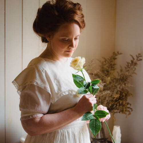 Woman in Victorian style dress holding a white rose